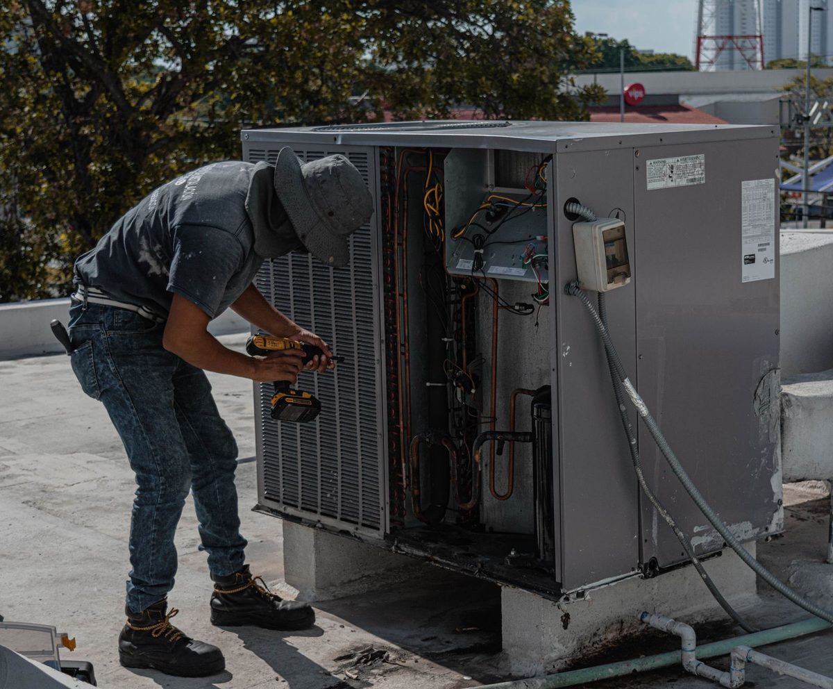 HVAC technician installing a new outdoor condenser unit as part of a system replacement